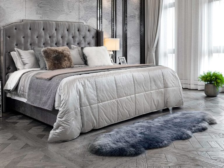 Moderne Schlafzimmer mit grauem Bett, eleganter Bettdecke und einem flauschigen Teppich.