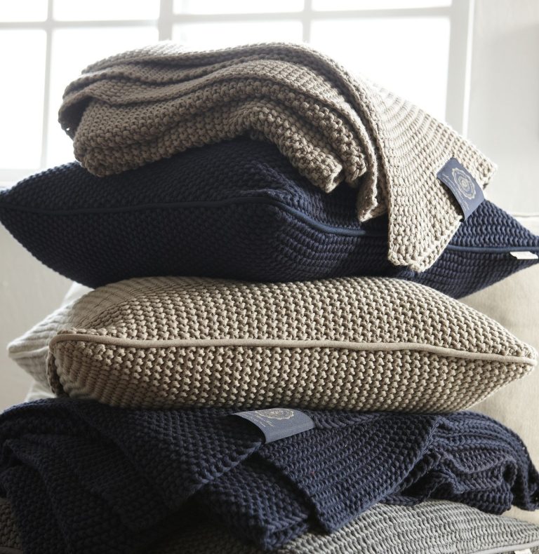 Gestapelte Decken und Kissen in verschiedenen Farben und Texturen.