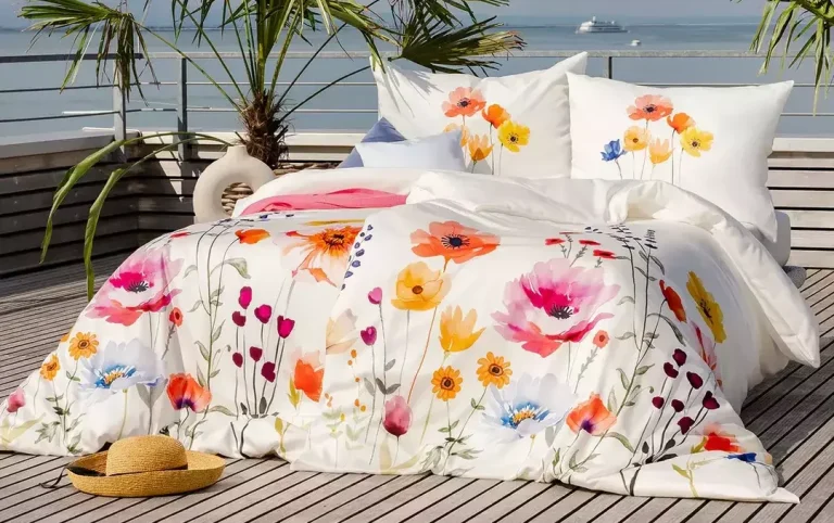 Bettwäsche mit bunten Blumenmustern auf einer Terrasse mit Meerblick.