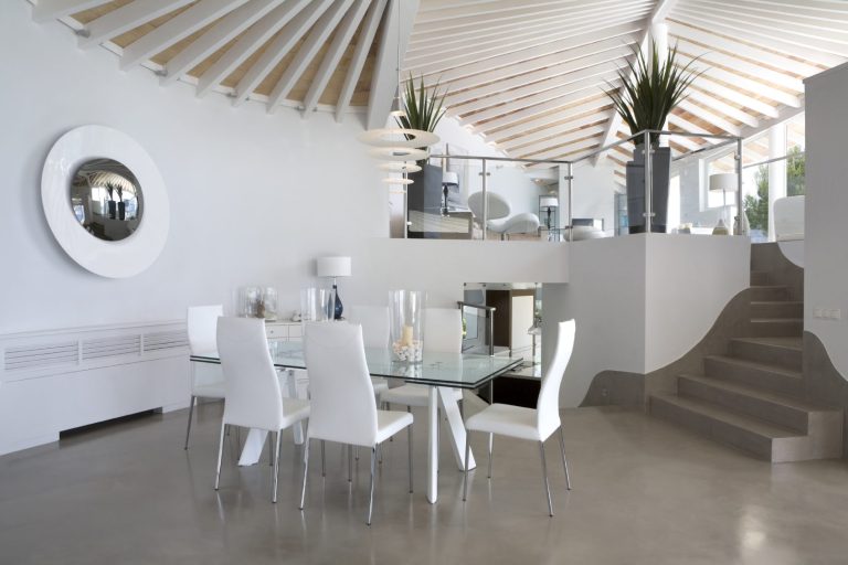 Moderne Dining-Umgebung mit Glas-Tisch, weißen Stühlen und stilvollem Holzdecke.