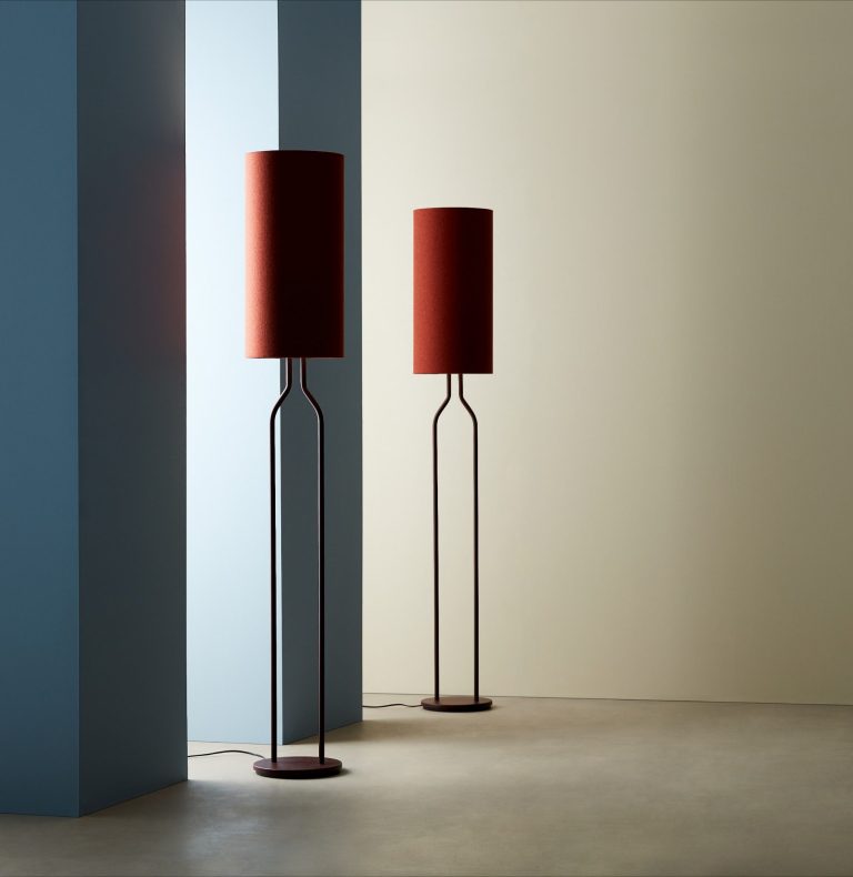 Zwei moderne Stehlampen mit roten Lampenschirmen vor einer hellen Wand.