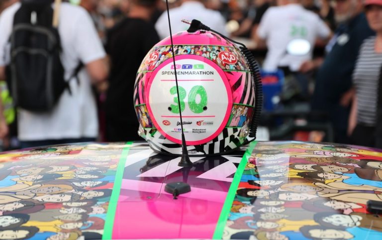 Motorsporthelm mit buntem Design und der Nummer 30 auf einem Auto.