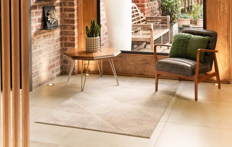 Bunter Teppich mit geometrischen Mustern und Blumen, umgeben von Kissen und einem Tisch.